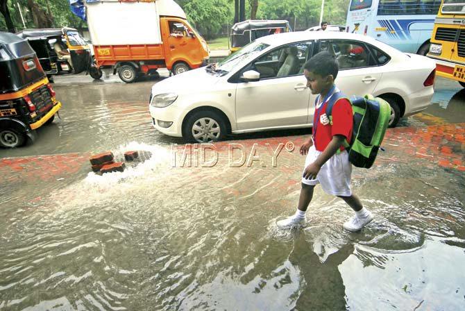 School children are forced to walk in filthy water gushing out from the manholes, exposing them to water-borne diseases, their parents complained. Pics/Sameer Markande