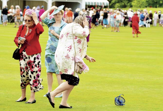 A woman chases a fly-away hat during a garden party in honour of the centenary of the Women