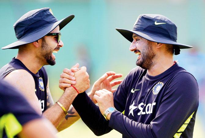 Test skipper Virat Kohli (left) and Harbhajan Singh share a light moment in Mirpur yesterday. Off-spinner Harbhajan is back in India’s Test squad after two years. PIC/AFP