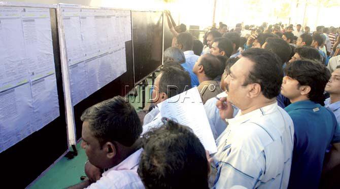 Participants in the MHADA lottery check a display board with the results at Rangsharda Auditorium in Bandra. Pics/Shadab Khan