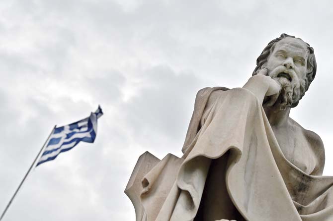 A statue of the ancient Greek philosopher Socrates stands in front of a Greek flag in Athens. Pics/AFP