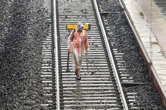 A railway worker walks on a train track during rain showers. Pic/AFP