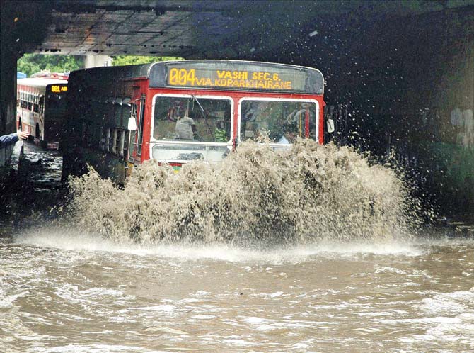 A bus goes through a water logged road after a downpour in Mumbai. Pic/PTI