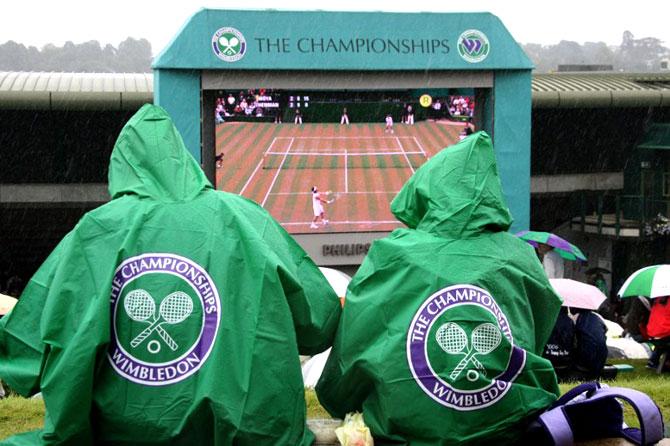 Tennis fans sitting on "Henman Hill" as rain delays the start of the sixth day of the 2007 Wimbledon championships. AFP PHOTO