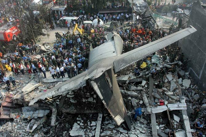Rescuers search for victims at the site where an air force cargo plane crashed in Medan, North Sumatra, Indonesia, Tuesday, June 30, 2015. The Hercules C-130 plane crashed into a residential neighborhood in the country