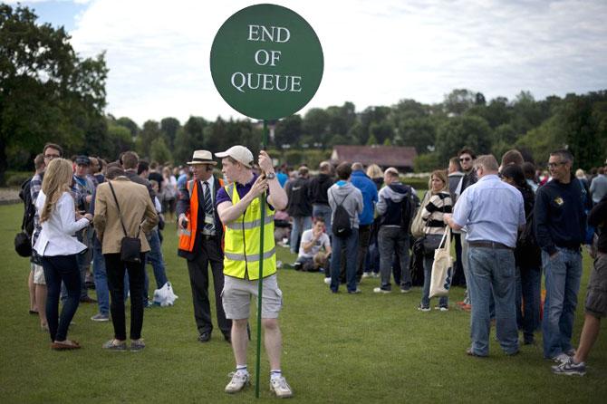 A steward holds a sign as tennis fans queue for tournament tickets to watch the action on the second day of the 2012 Wimbledon Championships. AFP PHOTO