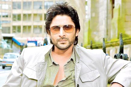 Why is Arshad Warsi's family flying down from Mumbai to Indore?