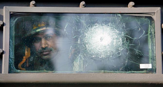 An Indian Army soldier looks through the damaged window of an army vehicle used in the assault at Mehasar village in Samba sector. 