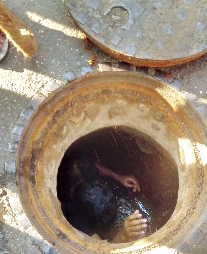A cleaner being lowered into a manhole in Lalbaug on March 11. He had no safety gear and had to remain inside for a long time