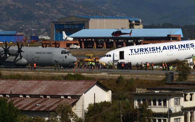 An Indian Air Force aircraft and Nepalese rescue workers are seen at the site where a Turkish Airlines plane slid off the tarmac at Kathmandu international airport on March 5, 2015.