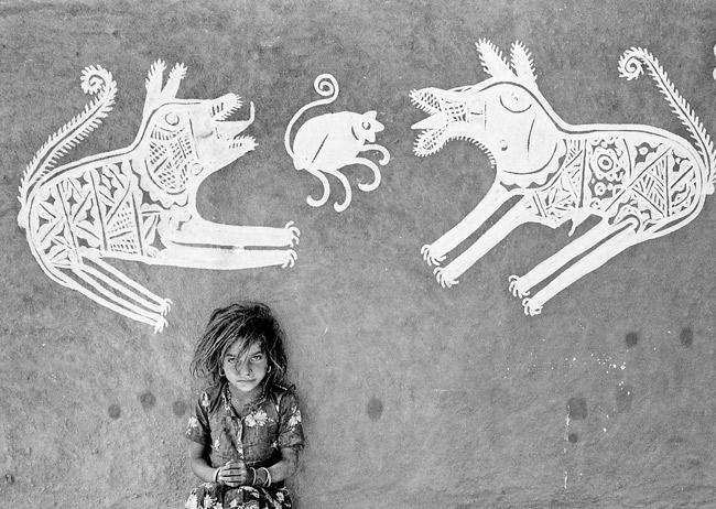 A young girl in front of mandana paintings, Rajasthan, 1970