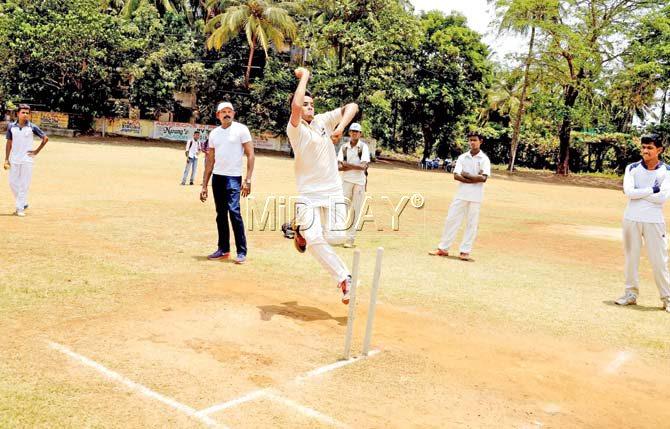 Coach Pradeep Sunderam watches a tennis ball bowler in action during MCA