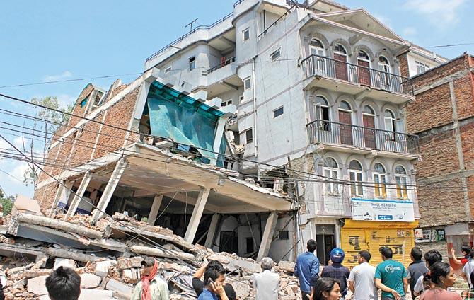 Bystanders watch as a building collapses in Kathmandu city