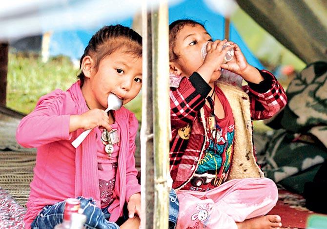 Nepalese children eat their food at a makeshift tent set up at a golf course in Gaushala, Kathmandu