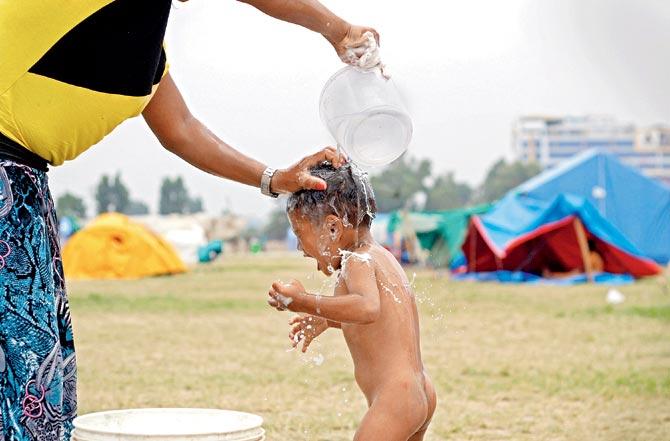 A woman gives her child a bath at a relief camp in Tundikhel, Kathmandu