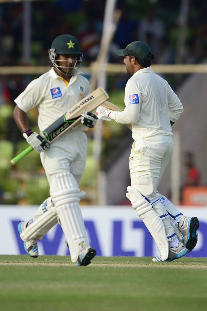 Pakistan cricketers Sarfraz Ahmed (R) and Asad Shafiq run between the wickets during the third day of the first cricket