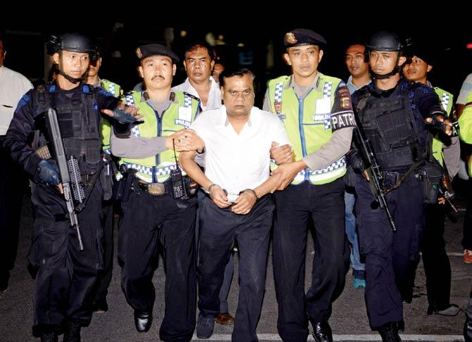 Chhota Rajan is escorted by police officers to the Bali airport to be deported to India. He is expected to arrive in New Delhi this morning. Pic/PTI