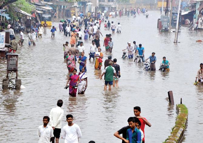 Land ahoy? People wade through a waterlogged street following heavy rains at Vyasarpadi in Chennai. Pic/PTI