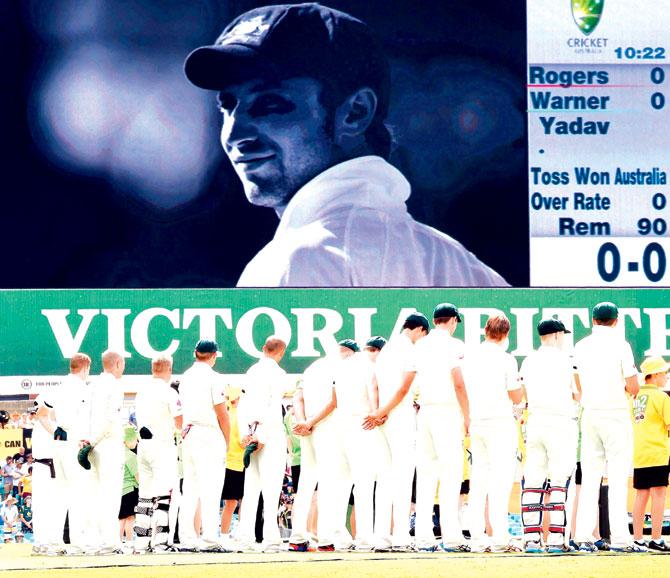 Jan 6, 2015: The Australian team pays tribute to their departed teammate, Phillip Hughes, whose image is flashed on the electronic scoreboard, before the start of the Sydney Test against India. Pic/AFP
