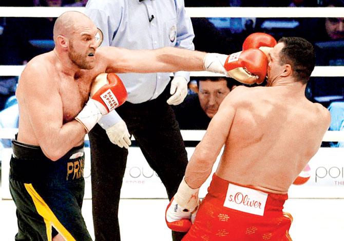 Tyson Fury (left) punches Wladimir Klitschko during their world heavyweight title fight. Pic: AP/PTI