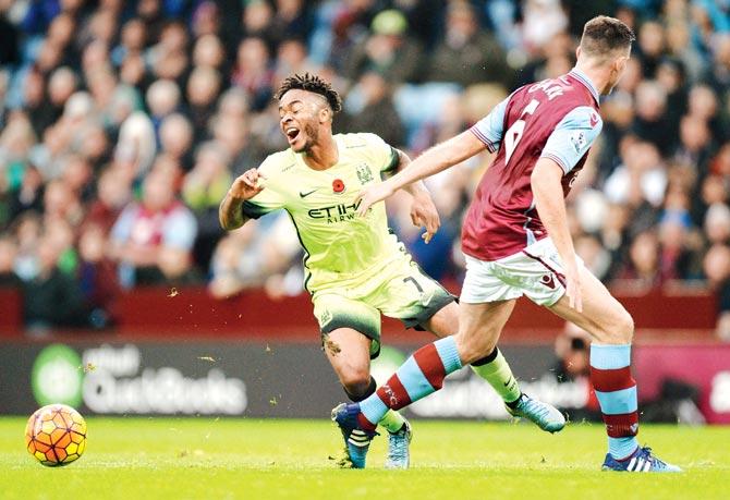 Man City striker Raheem Sterling (in green) falls after a challenge from Aston Villa