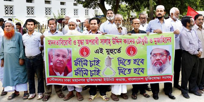 Bangladeshi freedom fighters who fought in the 1971 war hold a banner asking for the death penalty for Salauddin Quader Chowdhury (L) and Ali Ahsan Mohammad Mujahid (R). File Pic/AFP