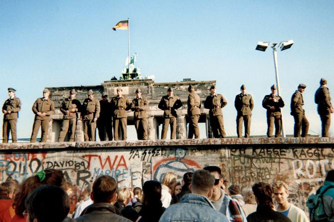East German border guards stand on a section of the Berlin wall,  with the Brandenburg gate in the background, on November 11, 1989 in Berlin. pic/afp