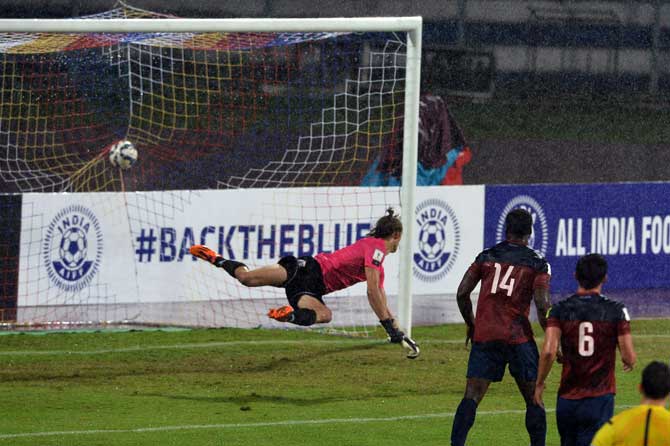Guam goalkeeper Douglas Herrick (L) attempts a save as India