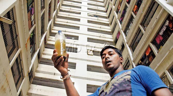 A resident of Omkar Housing Society holds up a sample of the water they have been receiving