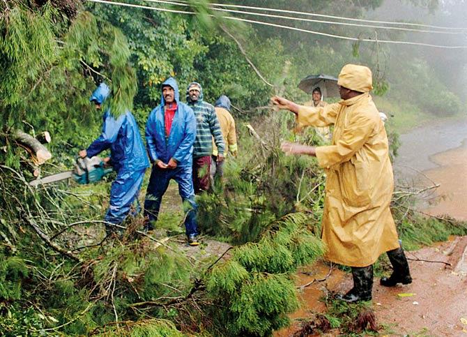 Municipal workers trying to clear a road in Ooty yesterday. Pic/PTI