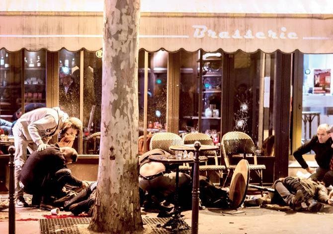 People on the pavement at the tarrasse of Café Bonne Biere in Paris, on November 13, 2015, following attacks in and around the city which left more than 120 people dead. AFP photo/Anthony Dorfmann