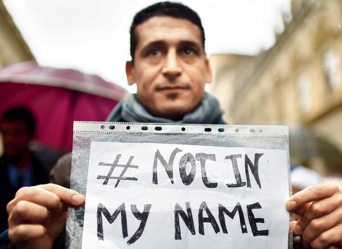 A man shows a placard reading “Not In my Name” during a demonstration  to speak out against terrorism a week after Paris attacks. pics/afp