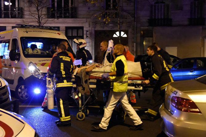 Rescuers evacuate an injured person on Boulevard des Filles du Calvaire, close to the Bataclan concert hall in central Paris. Pic/AFP