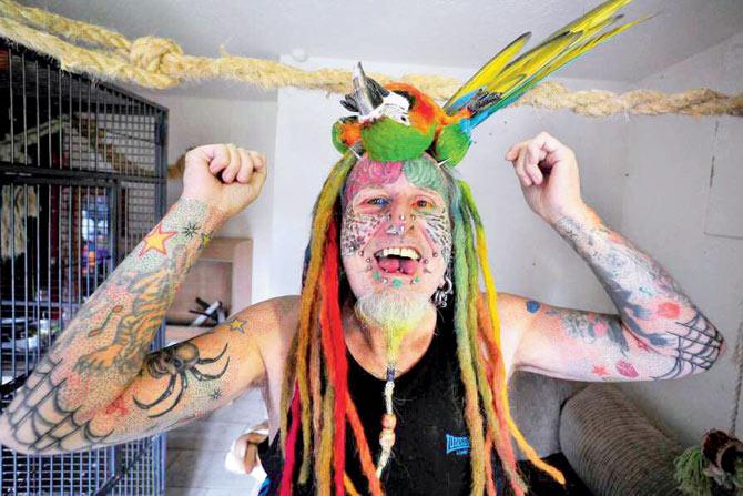Parrot man: Richards is obsessed by feathered pets Ellie, Teaka, Timneh, Jake and Bubi, and has his face tattooed with colourful feathers in a tribute. pic/Facebook