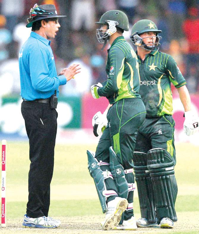 Shoaib Malik talks to umpire Ruchira Palliyaguruge after play was suspended due to bad light on Saturday. Pic:AP/PTI