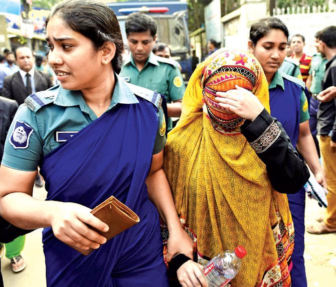 Bangladeshi security personnel escort Nritto Shahadat (right), the wife of Shahadat Hossain, to a court after her arrest in Dhaka yesterday. Pic/AFP