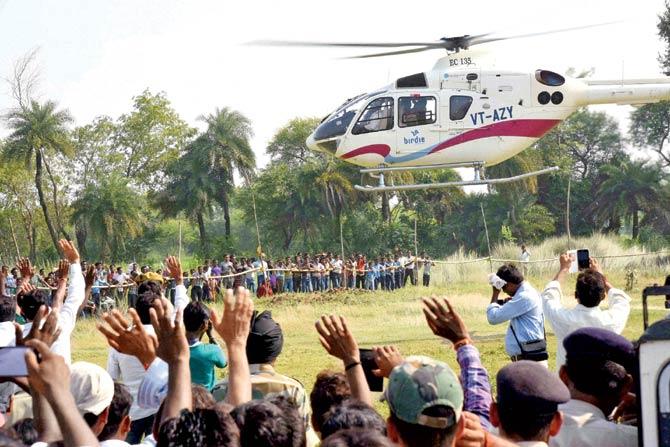 Supporters wave at the helicopter of Bihar Chief Minister Nitish Kumar as he leaves after an election rally in Imamganj area. Pic/PTI