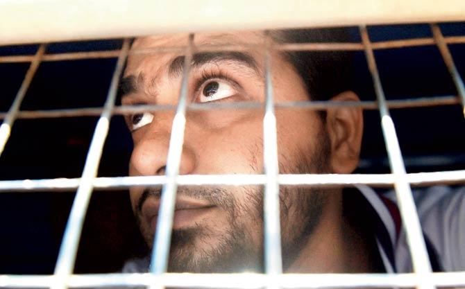 One of the convicts looks for his relatives from the police van on his way to court on Wednesday. The accused had not been allowed to meet their families since their conviction, but they caught a glimpse of their loved ones outside the courthouse yesterday. Pic/AFP
