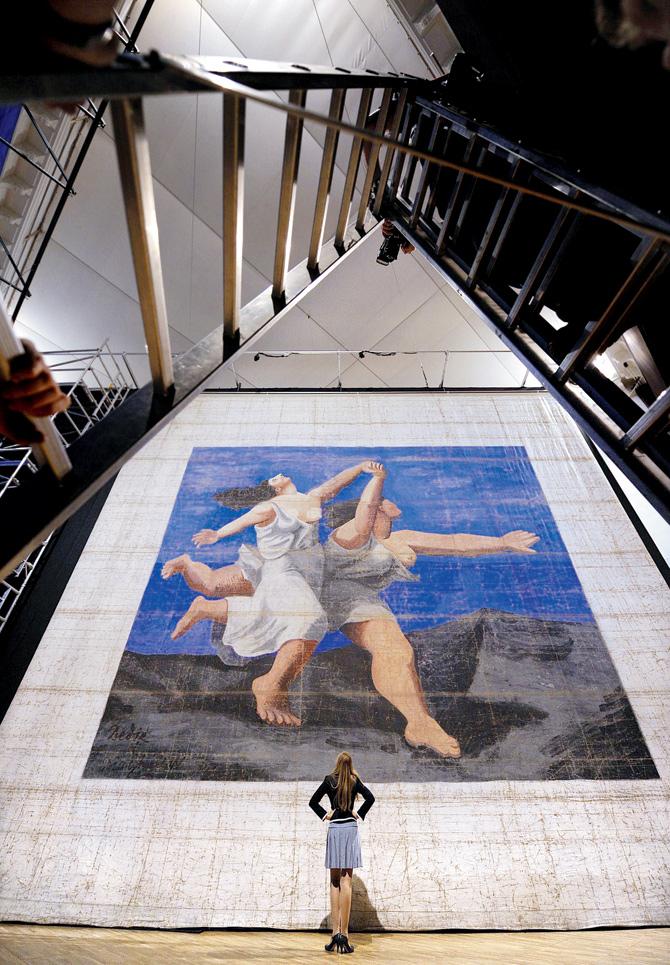 An employee poses in front of Le Train Bleu, one of the largest works by Pablo Picasso, at London’s Victoria and Albert Museum in 2010. Measuring 10.40 m by 11.72 m, the painting was created as the front cloth for ballet company, Ballets Russes’  Le Train Bleu performance in 1924. Pic/Afp