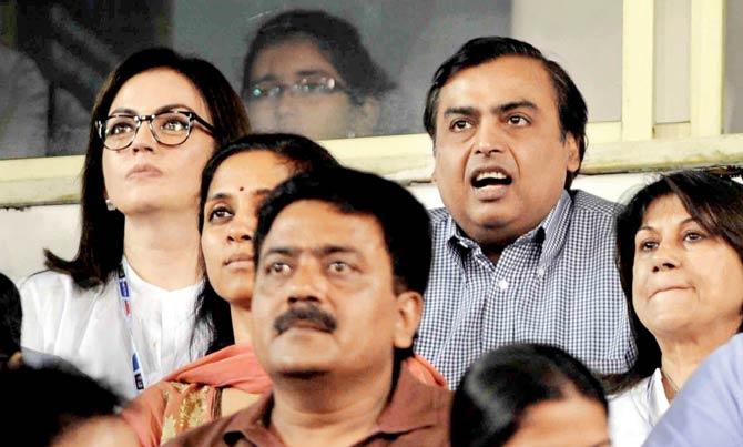 A file picture of Mukesh Ambani in the blue shirt and (right) the red shirt he wore for the India vs South Africa match 