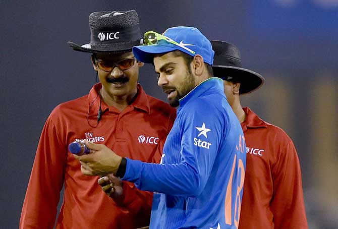 Virat Kohli shows a water bottle which fell on the pitch to the umpires