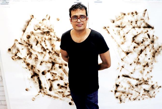 Jitish Kallat in his studio with the graphite drawings, Wind Study (The Hour of the Day of the Month of the Season), in the background