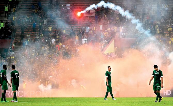 Saudi Arabia-s players walk off the pitch after flares were thrown by fans during their 2018 World Cup qualifier against Malaysia at the Shah Alam Stadium yesterday. The match was abandoned after the incident, which took place while Malaysia was 1-2 down in the 88th minute. The home fans, reportedly incensed at last week’s record 0-10 defeat to UAE, lit and threw fireworks on the pitch which filled the arena with smoke and led to players and team officials being escorted to the changing rooms.  Pic/AFP