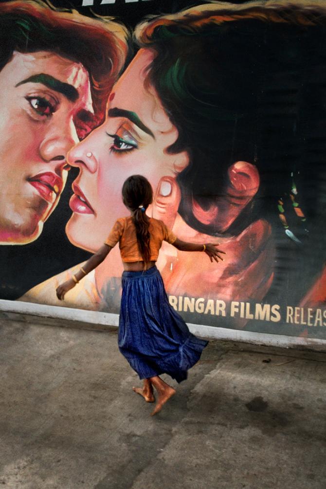 Young girl walking past a movie poster