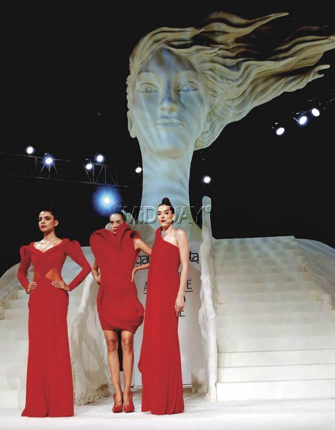 Models in structured silhouettes pose against the giant sculpture of a woman during Gaurav Gupta’s finale show