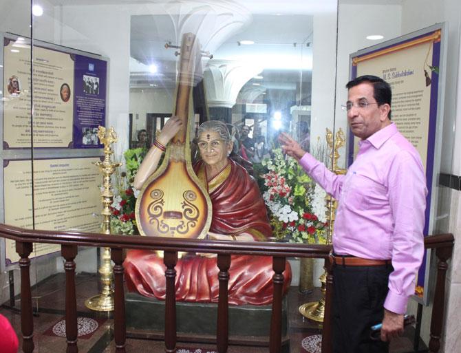 Dr. V Shankar, President of Shanmukhananda Sabha, standing beside the life-size statue of the late MS Subbulakshmi