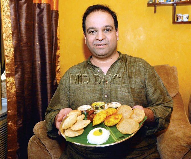 Soumitra Velkar holds a thali of vegetarian fare, prepared for a puja on the last day of the month of Shravan