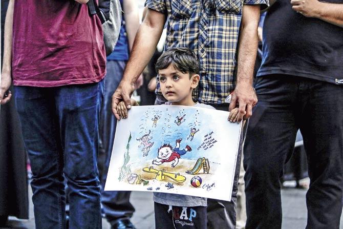 A young boy holds a painting showing children under water during a demonstration in Istanbul, after a boat carrying refugees sank as it crossed to the Greek island of Kos