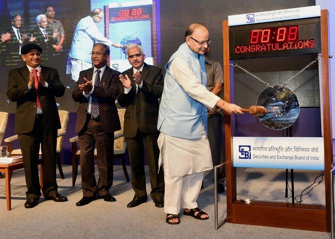 Union Finance Minister Arun Jaitley strikes a gong during an event announcing the FMC-SEBI merger in Mumbai on Monday