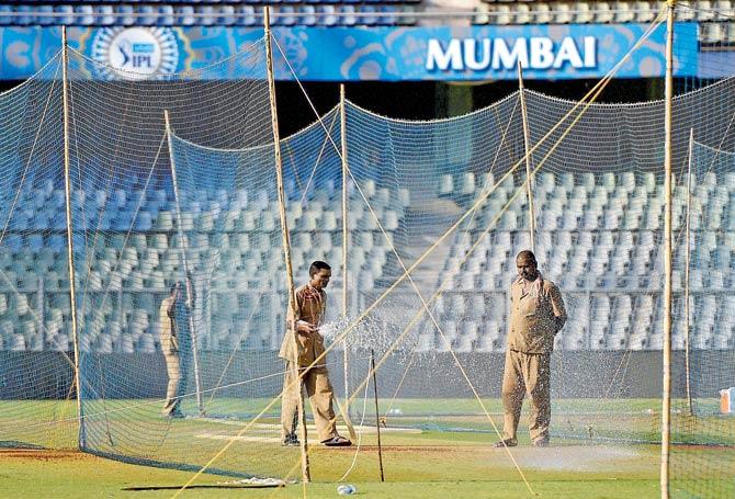Groundsmen water the pitch at the Wankhede stadium ahead of the opening IPL match that took place on April 9 in Mumbai. The Bombay High Court is currently hearing a PIL over the wastage of water for the tournament. Pic/PTI